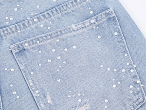 Vue détaillée de strass blancs sur la poche arrière d'un jean bleu clair