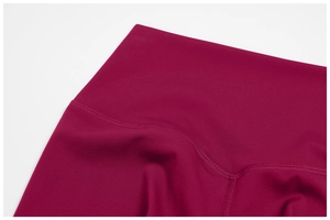 Detail of high-waist yoga shorts featuring reinforced flatlock stitching and dark rose fabric
