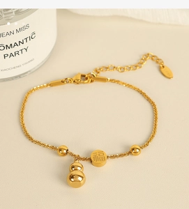 Detail of gold gourd charm bracelet with Fu character pendant and woven chain texture