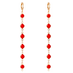 Close-up of long gold drop earrings featuring six round red crystals in a vertical setting