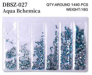 Flat lay of mixed size Aqua Bchemica flatback nail crystals in a 6-grid organizer box