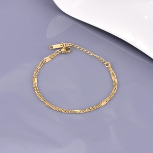 Minimalist double-layered gold bracelet with K18 engraving on a grey reflective background