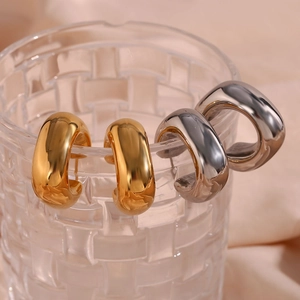 Minimalist square hollow stainless steel earrings in gold and silver hung on glass