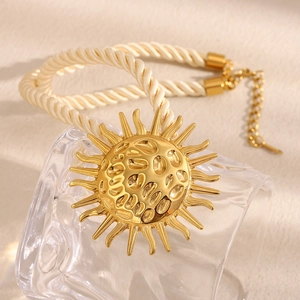 Detail of 18K gold sun pendant necklace with beige braided rope and metal extension chain