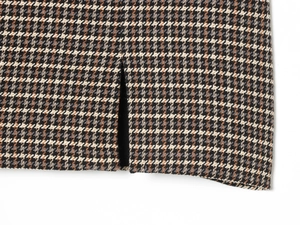 Detailed close-up of brown and beige plaid fabric with high-quality slit hem detail