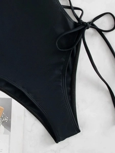 Close-up of black one-piece swimsuit featuring side lace-up ties and high-cut leg detail