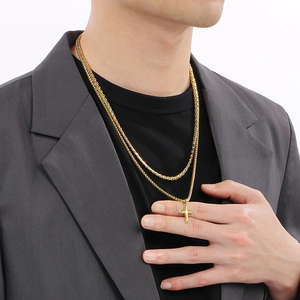 Men's double layer gold cross pendant necklace on model with Cuban link and blazer