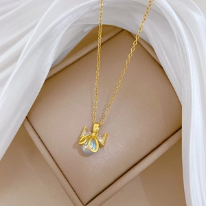 Detail of gold titanium necklace with pearl bow pendant and blue gemstone inlay