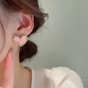 Orecchini a cuore rosa e oro indossati da una modella per un look dolce e molto femminile