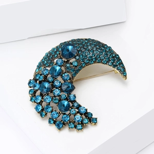 Close-up of crescent moon brooch with blue crystals on a golden base and geometric stand