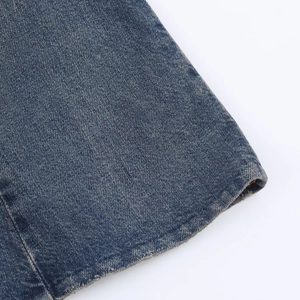 Detail of washed denim midi dress featuring frayed hem and textured blue fabric