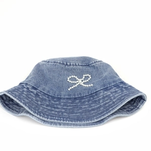Détail d'un chapeau bob en denim bleu clair avec un nœud décoratif en perles blanches chic