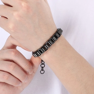 Détail macro du bracelet gourmette en acier inoxydable noir brillant porté au poignet