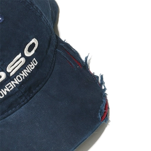 Macro detail of distressed navy baseball cap with white embroidery and frayed brim edge