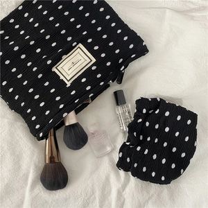 Detailed view of polka dot pleated makeup bag and matching headband with logo tag