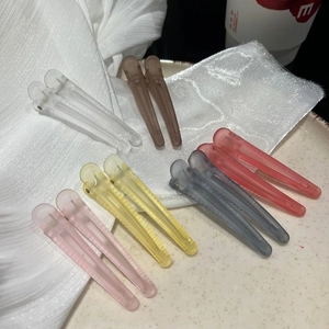 Detailed view of matte duckbill hair clips in various pastel colors on a soft fabric