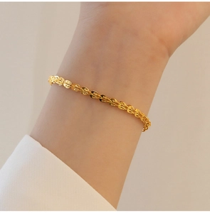 Dettaglio di un bracciale retrò a coda di fenice placcato oro 18K al polso di una donna