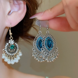 Dettaglio di orecchini vintage con nappe perle e gemme indossati per un look di lusso