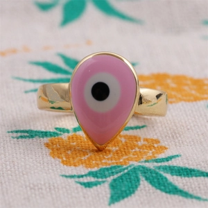 Détail macro d'une bague goutte en émail rose avec œil protecteur doré