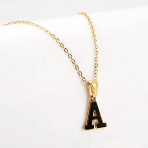 Macro detail of gold-plated letter A pendant with black enamel inlay on a delicate chain
