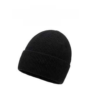 Close-up of black ribbed knit beanie featuring a metallic oval brand logo on the fold