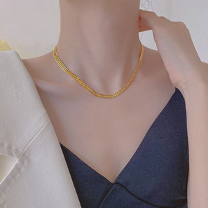 Close-up of a gold-plated titanium steel woven chain necklace on a model's collarbone