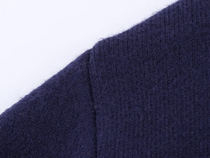 Détail d'un pull en maille violette montrant des coutures de qualité et une texture laine