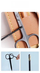 Detail of black stainless steel ear pick with spiral head and portable brown leather case