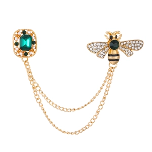 Detail of emerald cut green gem brooch with bee motif and gold linked chains