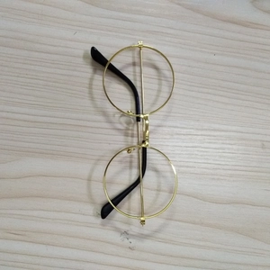 Vintage gold metal round frame glasses with black temple tips on a wooden background