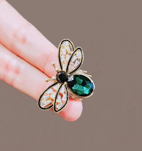 Detail of a vintage bee brooch with green gemstone body and sparkling zircon wings