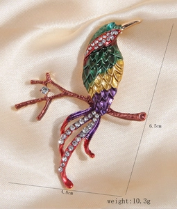 Detail shot of multicolored enamel magpie brooch with rhinestones on silk background