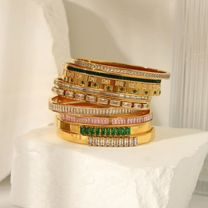 Detail showing stacked 18K gold plated bangles with emerald, pink gems and zircon