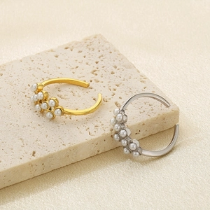 Detailed view of gold and silver open rings with small pearls on stone surface