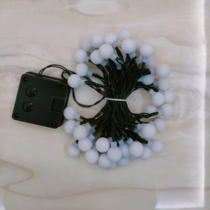 Detail of LED frosted globe solar string lights with green wire and black controller