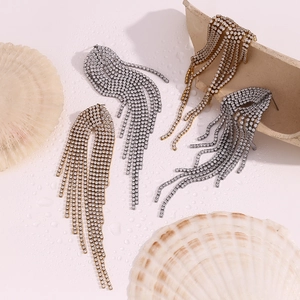 Macro detail of gold and silver tassel earrings with zircon stones on shell background