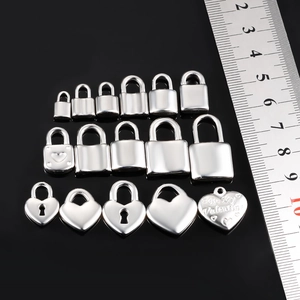 Polished stainless steel heart and lock charms in various sizes measured with a ruler