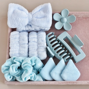 Detail view of light blue spa headband, wristbands, hair clips, and makeup puffs set