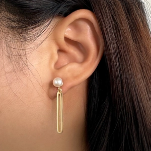 Close-up of 925 sterling silver earrings with baroque pearls and gold rectangle pendants
