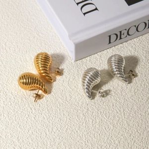 Detail shot of gold and silver teardrop earrings with elegant striped metal texture