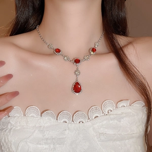 Dettaglio di collana vintage a goccia con gemma rossa e diamanti su una modella