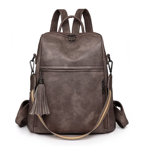 Macro detail of dark brown vintage backpack with fringe and striped shoulder strap