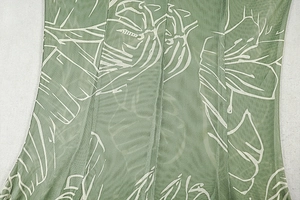 Close-up of green mesh fabric with white leaf prints on a vintage A-line dress
