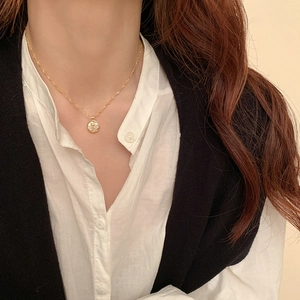 Close-up of golden tulip flower pendant with mother of pearl inlay on model