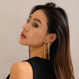 Close-up of golden bow earrings with long snake chain tassels on a model side profile