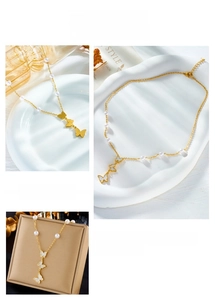 Dettaglio della collana di perle dorata con pendenti a farfalla a strati e inserti in conchiglia