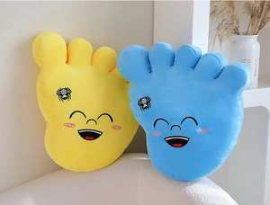Detail of yellow and blue plush foot pillows with cartoon smiles on a white sofa