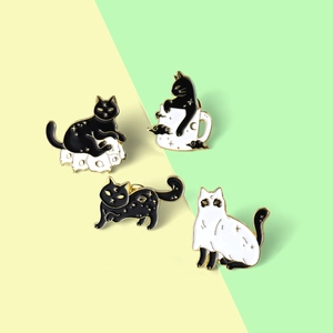 Detail of four spooky black and white cat enamel pins with gold trim for Halloween decor