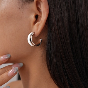 Detail view of 18k gold plated geometric C-shape earrings with white enamel on model