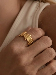 Close-up of irregular geometric gold stainless steel ring worn on a finger